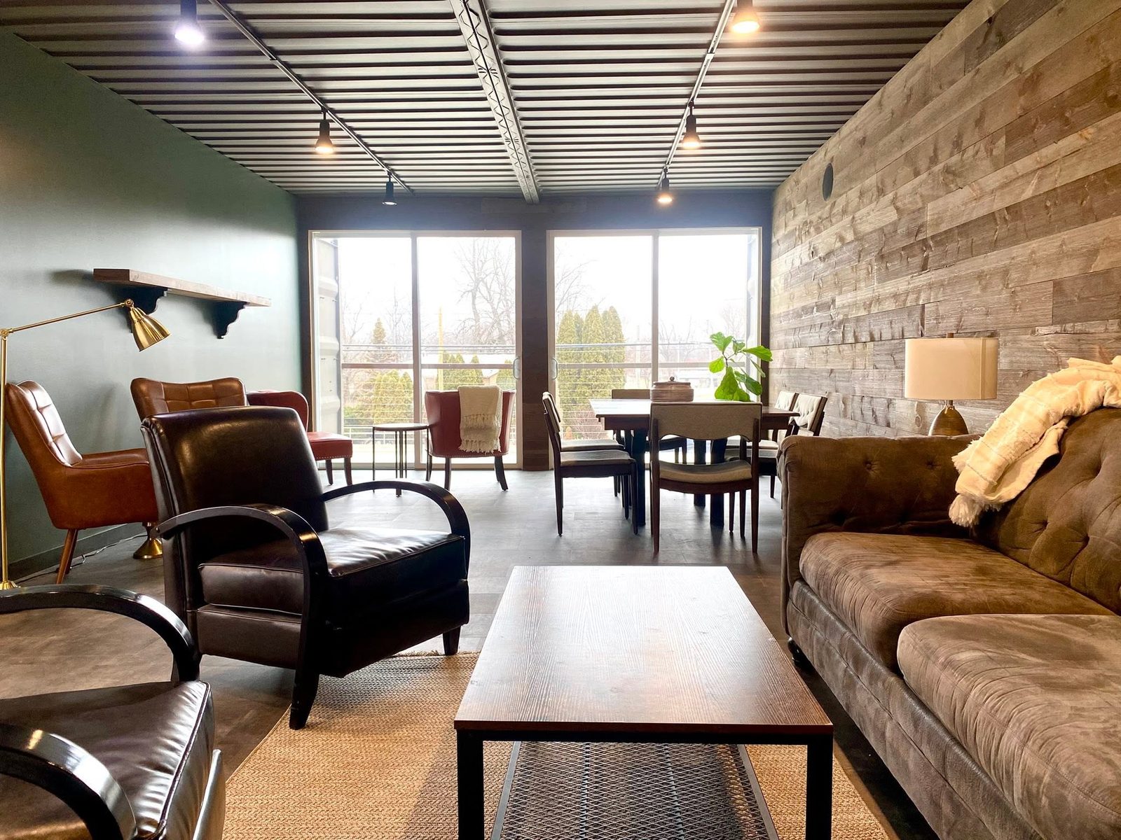 The upstairs lounge — leather armchairs and a sofa under the container ceiling, windows onto the deck